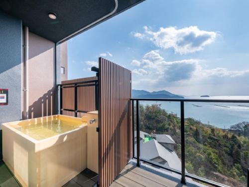 a bathroom with a tub and a view of the ocean at LiVEMAX RESORT Miyahama Ocean View in Hatsukaichi