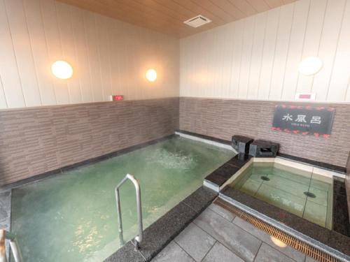 a jacuzzi tub in a room with a sign at LiVEMAX RESORT Miyahama Ocean View in Hatsukaichi