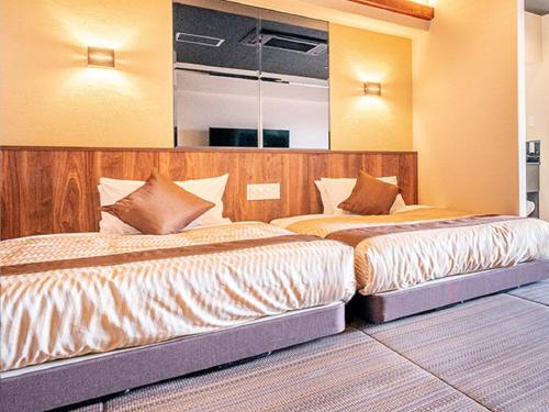 two beds in a hotel room with two bedsvisor at LiVEMAX RESORT Miyahama Ocean View in Hatsukaichi