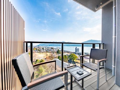a balcony with two chairs and a table at LiVEMAX RESORT Miyahama Ocean View in Hatsukaichi