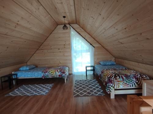 two beds in a wooden room with a window at Stodoły Hołosanka 600-065-145 in Polańczyk