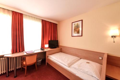 a hotel room with a bed and a desk at Hotel ADRIA München in Munich