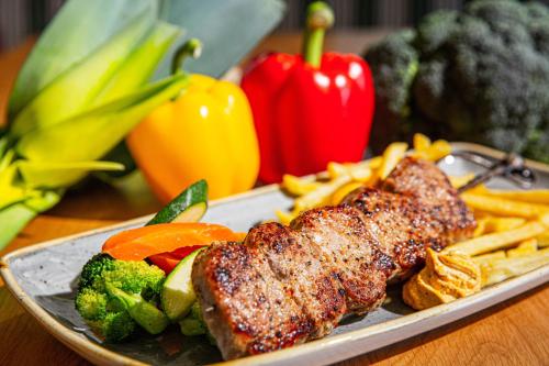 a plate of food with meat and french fries and vegetables at Voralpenhotel Schmoller in Sankt Georgen im Attergau