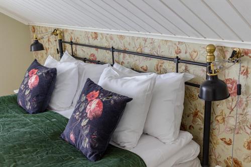 a bed with white pillows and green sheets at Rosenhill Bed & Breakfast in Grebbestad