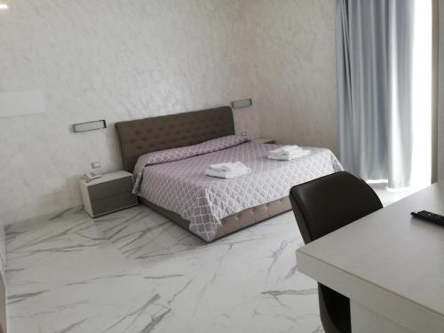 a bedroom with a bed and a table and a desk at Hotel Presidente in Porto Cesareo