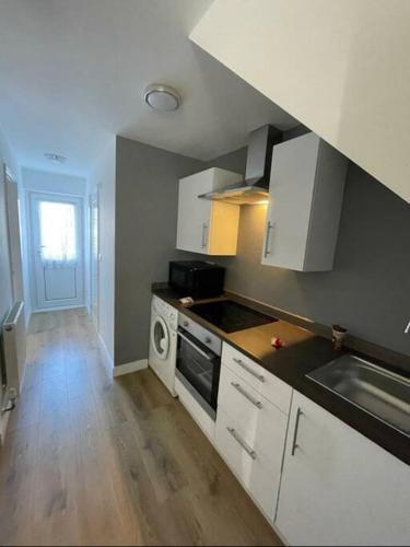 uma cozinha com armários brancos e um forno com placa de fogão em Basingstoke 1x Double bed and Sofa bed em Sherborne Saint John
