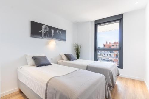 two beds in a white room with a window at Luxury Penthouse Allonbay Village & SPA in Villajoyosa