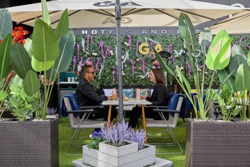 two people sitting at a table in front of plants at Pullman London St Pancras in London