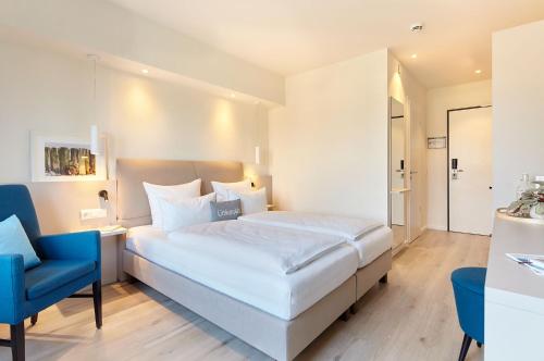 a bedroom with a large bed and a blue chair at Familotel Strandkind in Pelzerhaken