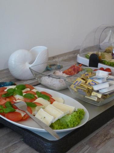 a table with a plate of food with cheese and vegetables at Pension Haus Baltic in Dahme