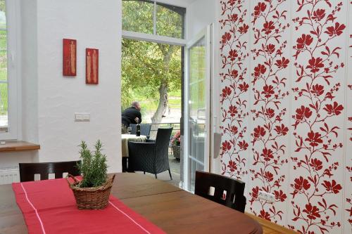 a dining room with a table with a red floral wallpaper at Ferienwohnungen by Weingut Hommes in Ernst Mosel in Ernst