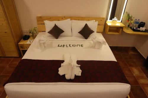 a bedroom with a large white bed with a towel on it at Royal Destiny Resort in Malaiyāndipattanam