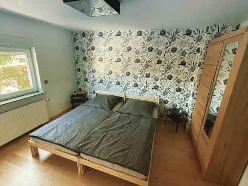 - une chambre avec un lit dans une pièce avec du papier peint dans l'établissement gehobene Ferienwohnung im schönen Odenwald, à Fürth