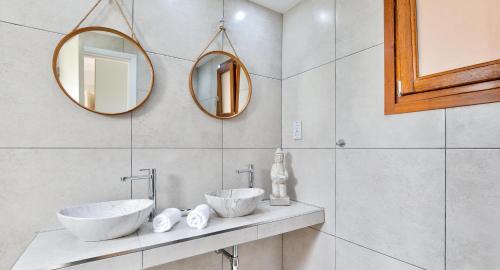 two sinks in a bathroom with two mirrors at Apartment KZ01 - Modern ground floor apartment in the heart of Aphrodite Hills Resort in Kouklia