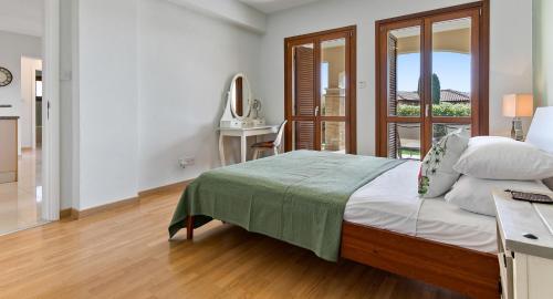a bedroom with a bed and a desk and a window at Apartment KZ01 - Modern ground floor apartment in the heart of Aphrodite Hills Resort in Kouklia