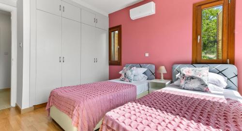 two beds in a room with pink walls at Apartment KZ01 - Modern ground floor apartment in the heart of Aphrodite Hills Resort in Kouklia