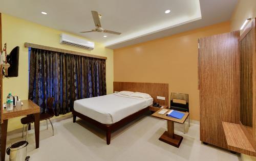 a bedroom with a bed and a desk and a table at Hotel Fortune in Rāmeswaram