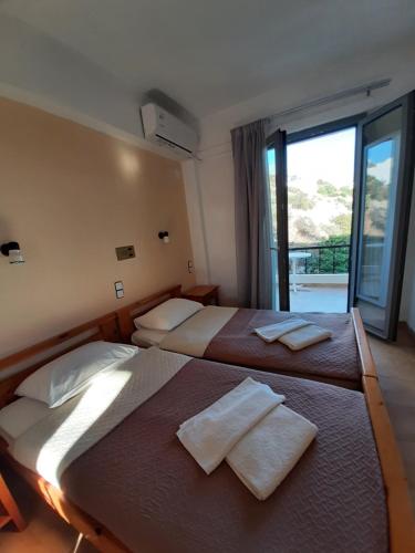 two beds in a room with a large window at Ostria in Agia Galini