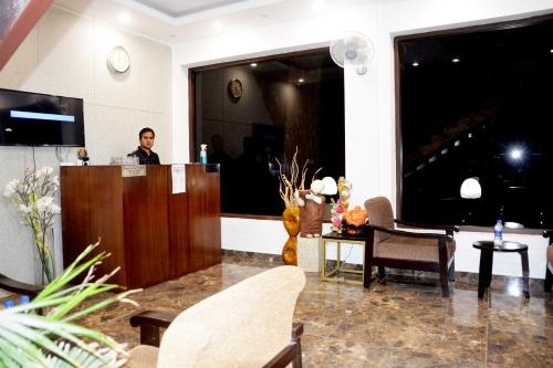 a man standing at a podium in a hotel lobby at The Golden Sunrise Hotel in Nainital