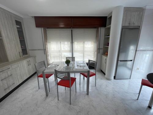 a dining room with a table and red chairs at Alojamiento Apostol 1 in Melide