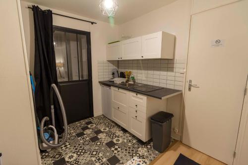 a small kitchen with white cabinets and a black door at Le petit Studio proche gare in Flers