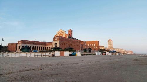 an empty beach with a large building in the background at SWEET HOME & WELLNESS affittacamere in Nettuno