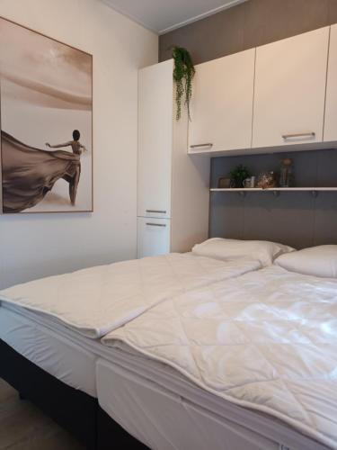a large bed in a bedroom with a painting on the wall at Het Yorritje - tiny house nabij kust in Dirkshorn