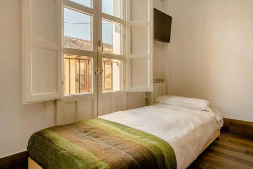 Schlafzimmer mit einem großen Bett und einem Fenster in der Unterkunft Increíble Apto 3º San Miguel CentroCatedral+Parking+Wifi in Granada