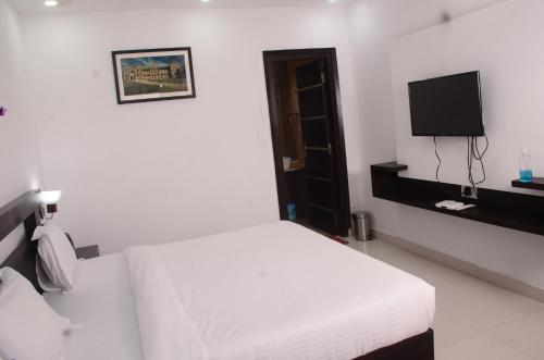 a white bedroom with a bed and a tv at The Golden Sunrise Hotel in Nainital
