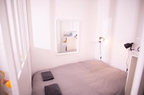 a small white room with a bed and a mirror at Charmant Studio au coeur de Jaurès in Belfort