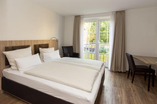 a bedroom with a bed and a table and a window at Hotel Jesteburger Hof in Jesteburg