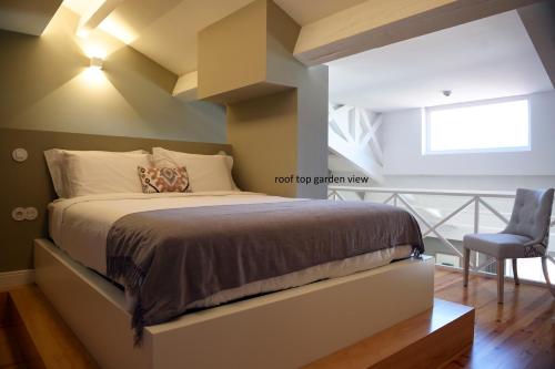 a bedroom with a large bed and a chair at Trendy Flats Fontainhas in Porto