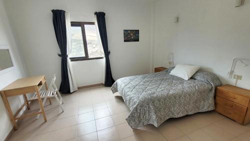 a bedroom with a bed and a desk and a window at Apt con piscina La Laja, La Restinga (El Hierro) in La Restinga