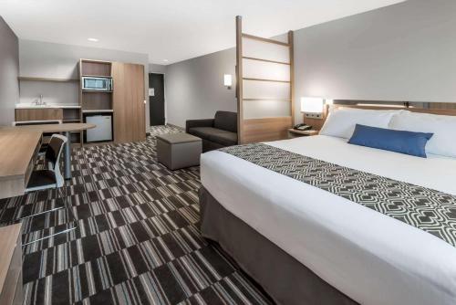 ein Hotelzimmer mit einem großen Bett und einem Schreibtisch in der Unterkunft Microtel Inn & Suites by Wyndham - Penn Yan in Penn Yan