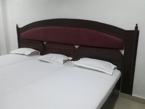 a bed with two white pillows and a wooden headboard at Hotel Sorrento Guest house Anna Nagar East Metro Shenoy Nagar metro budget monthly daily rooms in Chennai