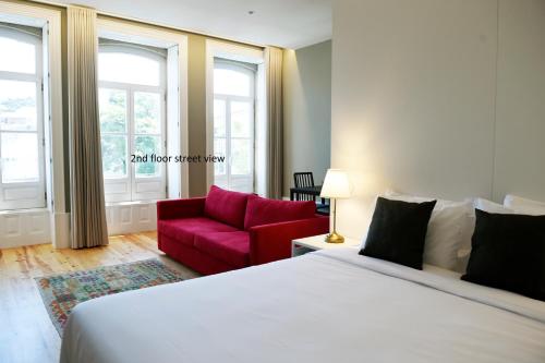 een slaapkamer met een bed en een rode bank bij Trendy Flats Fontainhas in Porto