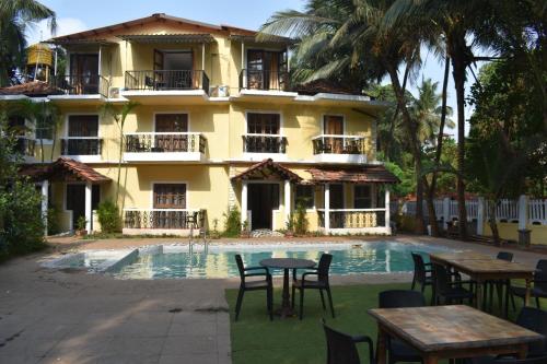 a hotel with tables and chairs in front of a pool at Villa Fatima Comfort in Calangute