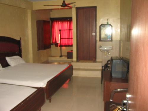 a bedroom with two beds and a tv and a window at Hotel Sorrento Guest house Anna Nagar East Metro Shenoy Nagar metro budget monthly daily rooms in Chennai