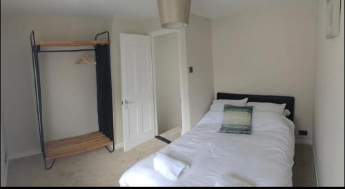 sypialnia z białym łóżkiem i lustrem w obiekcie A quaint Wymondham cottage w mieście Norwich