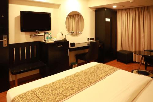 a hotel room with a bed and a desk and a television at Quality Inn Bez Krishnaa in Visakhapatnam