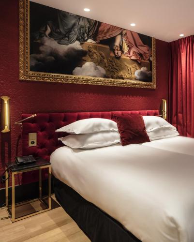 a bedroom with a large bed with a painting on the wall at Eiffel Petit Louvre in Paris