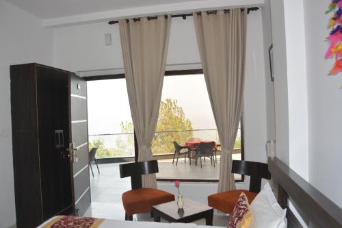 a bedroom with a large window with a table and chairs at The Golden Sunrise Hotel in Nainital