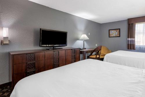 a hotel room with two beds and a flat screen tv at Suburban Studios Lafayette in Lafayette