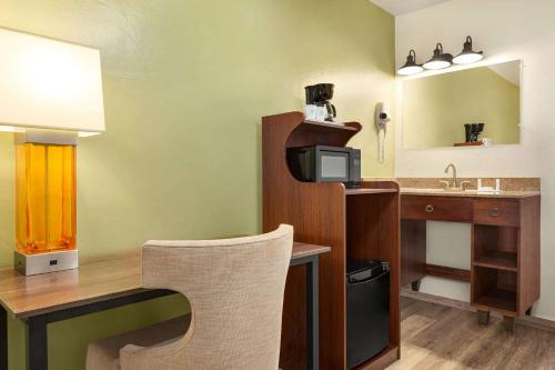 a room with a desk with a computer and a sink at Baymont by Wyndham Fort Bragg in Fort Bragg