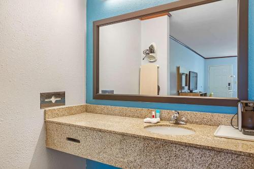 a bathroom with a sink and a large mirror at Days Inn by Wyndham Foley in Foley