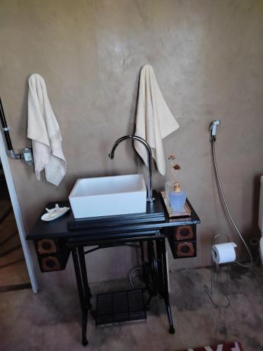 a bathroom with a desk with a sink and towels at Yurt Tree, romântico e confortável, experiência unica in Jacutinga