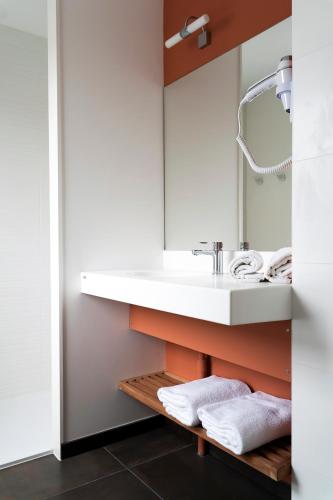 une salle de bain avec un lavabo et un miroir dans l'établissement HOTEL LE 25, à Andernos-les-Bains