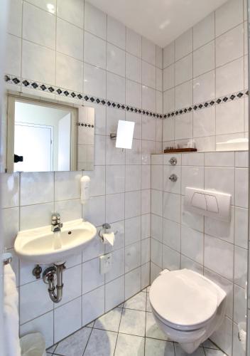 a white bathroom with a toilet and a sink at Hotel ADRIA München in Munich