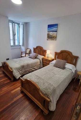 two beds in a room with wooden floors at Apartamentos Casa do Pan in Corme-Puerto