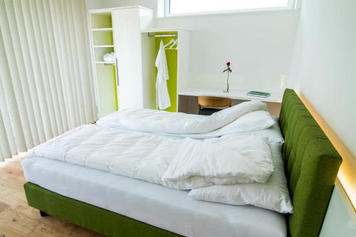a bed with white sheets and a desk in a room at baadhaus in Traunkirchen